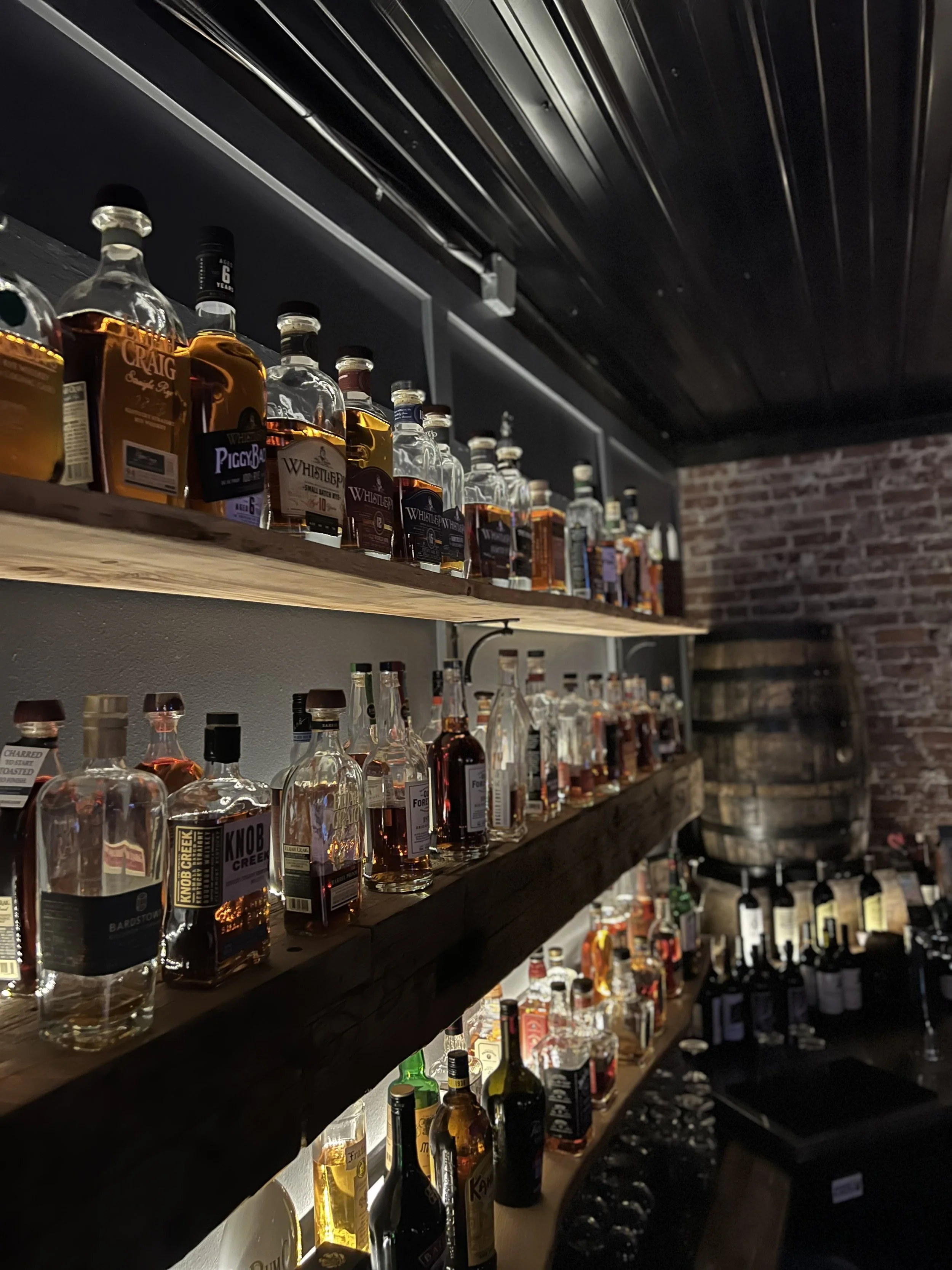 Over 100 bottles of bourbon, rye and whiskey on shelves along the exposed brick wall at Whiskey & Water in Blue Ridge, Georgia
