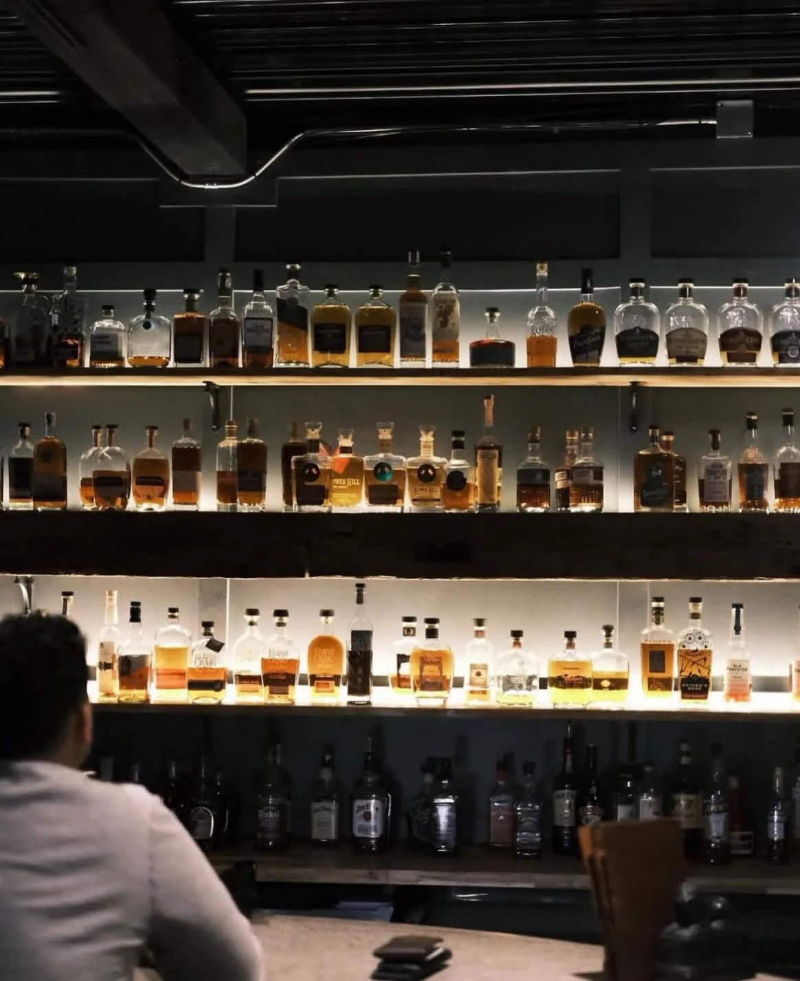 Backlit shelves of bourbon behind the bar at Whiskey & Water, a bourbon bar in the North Georgia mountains