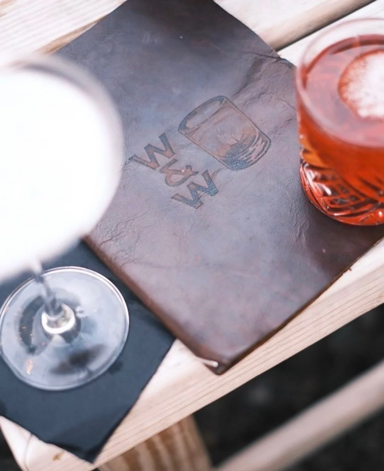 A Whiskey & Water embossed leather menu on the table beside an original cocktail