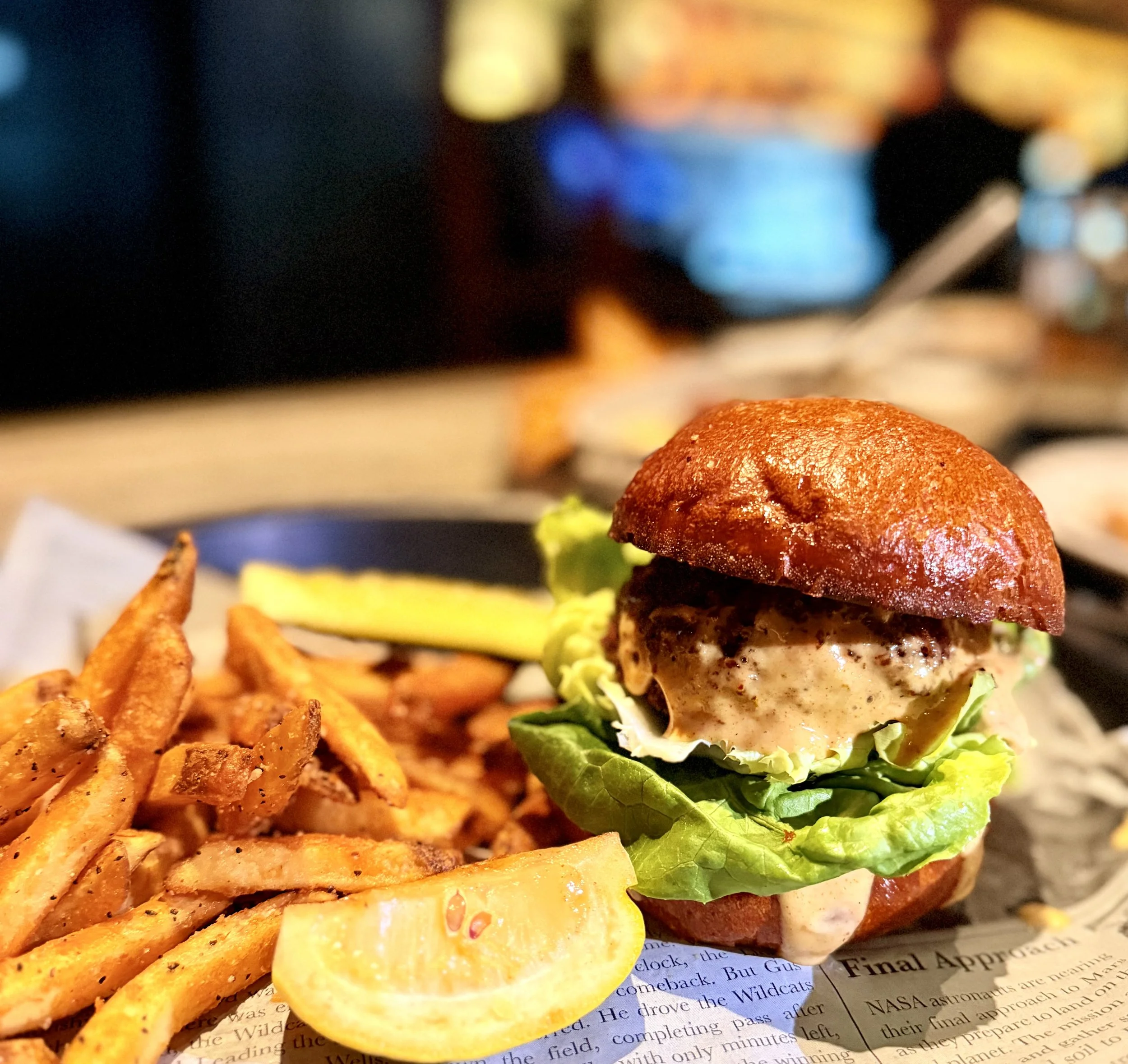 A seafood sandwich on a brioche bun with seasoned fries at Whiskey & Water