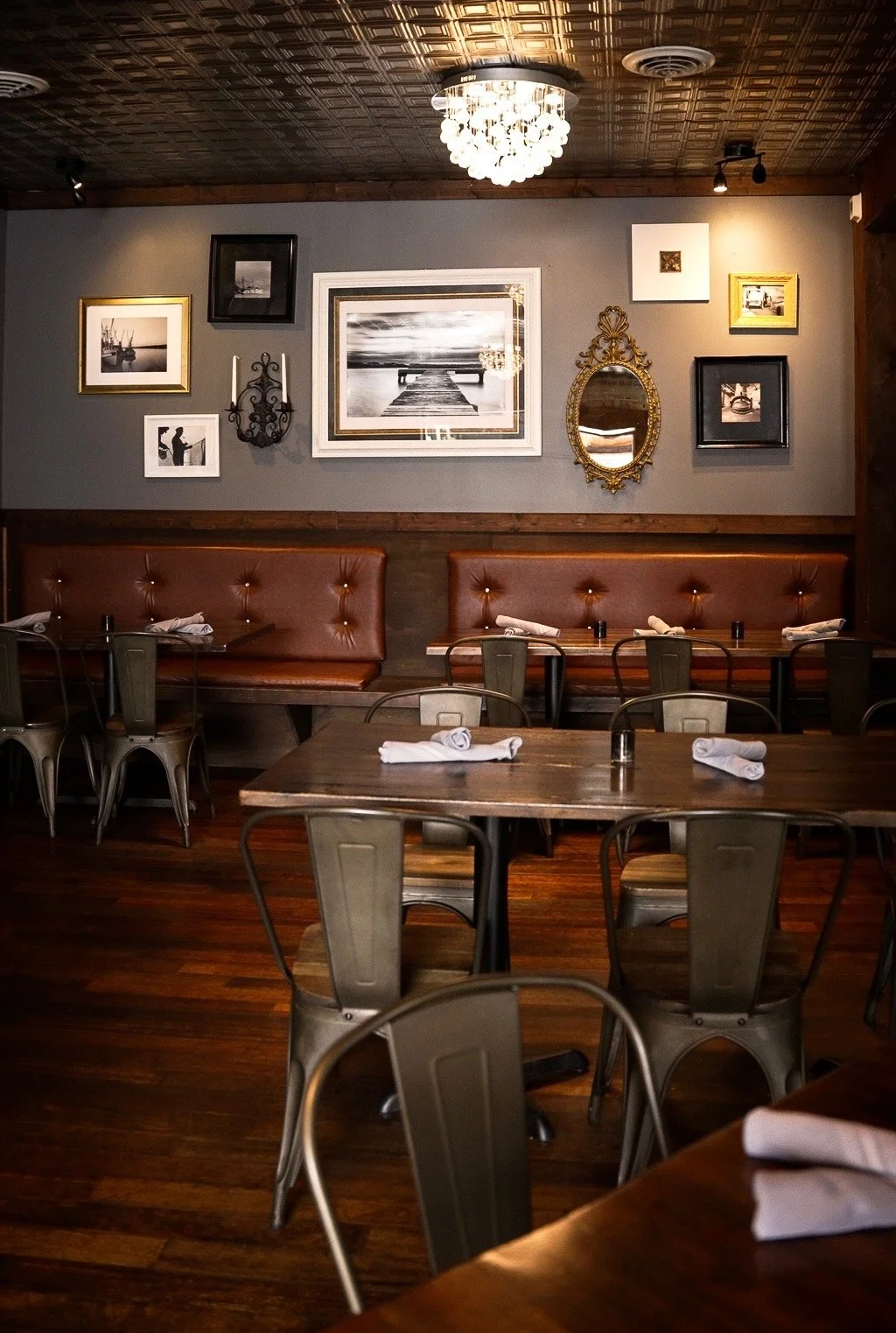 A corner booth at Whiskey & Water beneath framed nautical prints and a warm chandelier