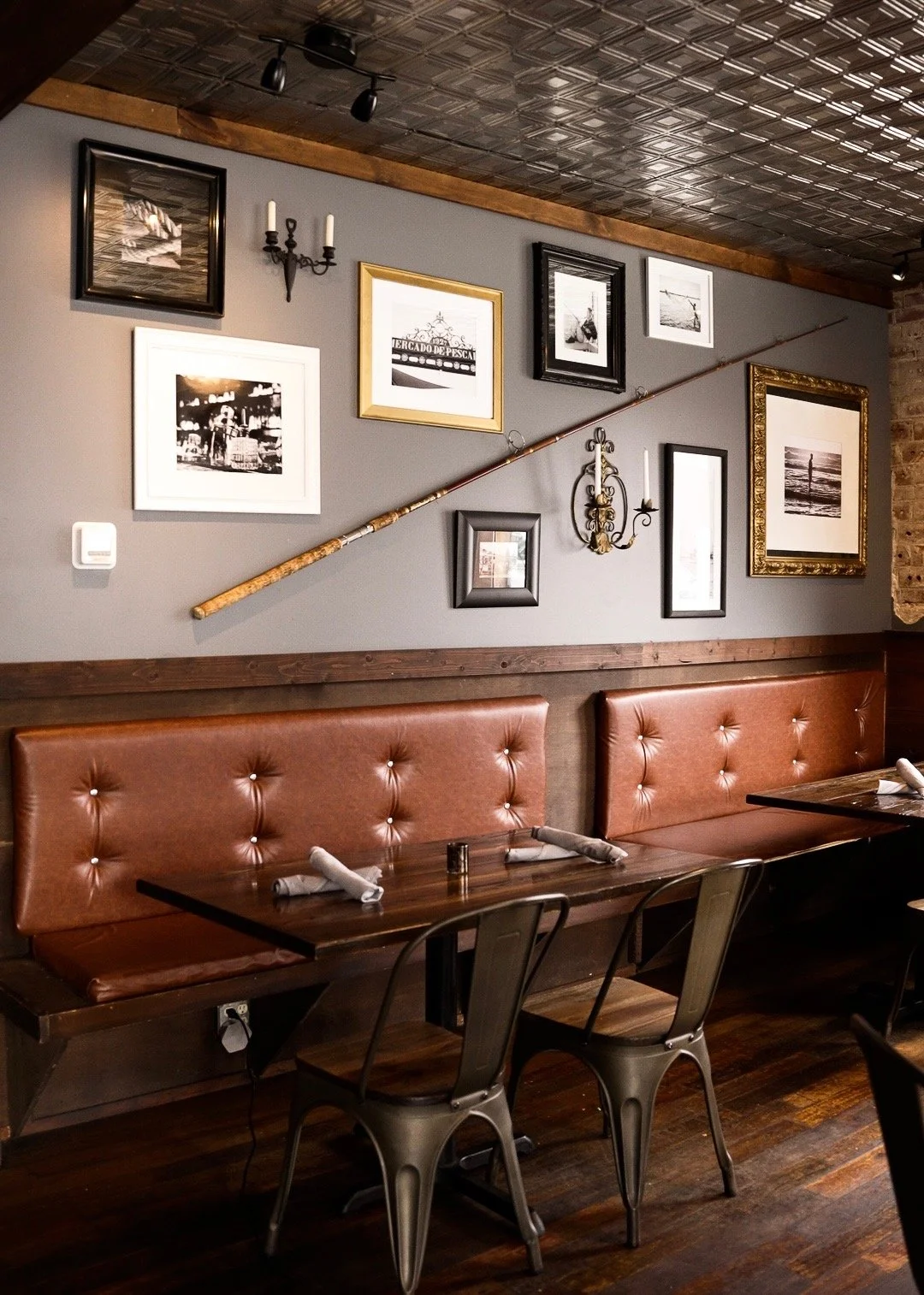 Banquette seating beneath framed black-and-white nautical photographs in the Whiskey & Water dining room