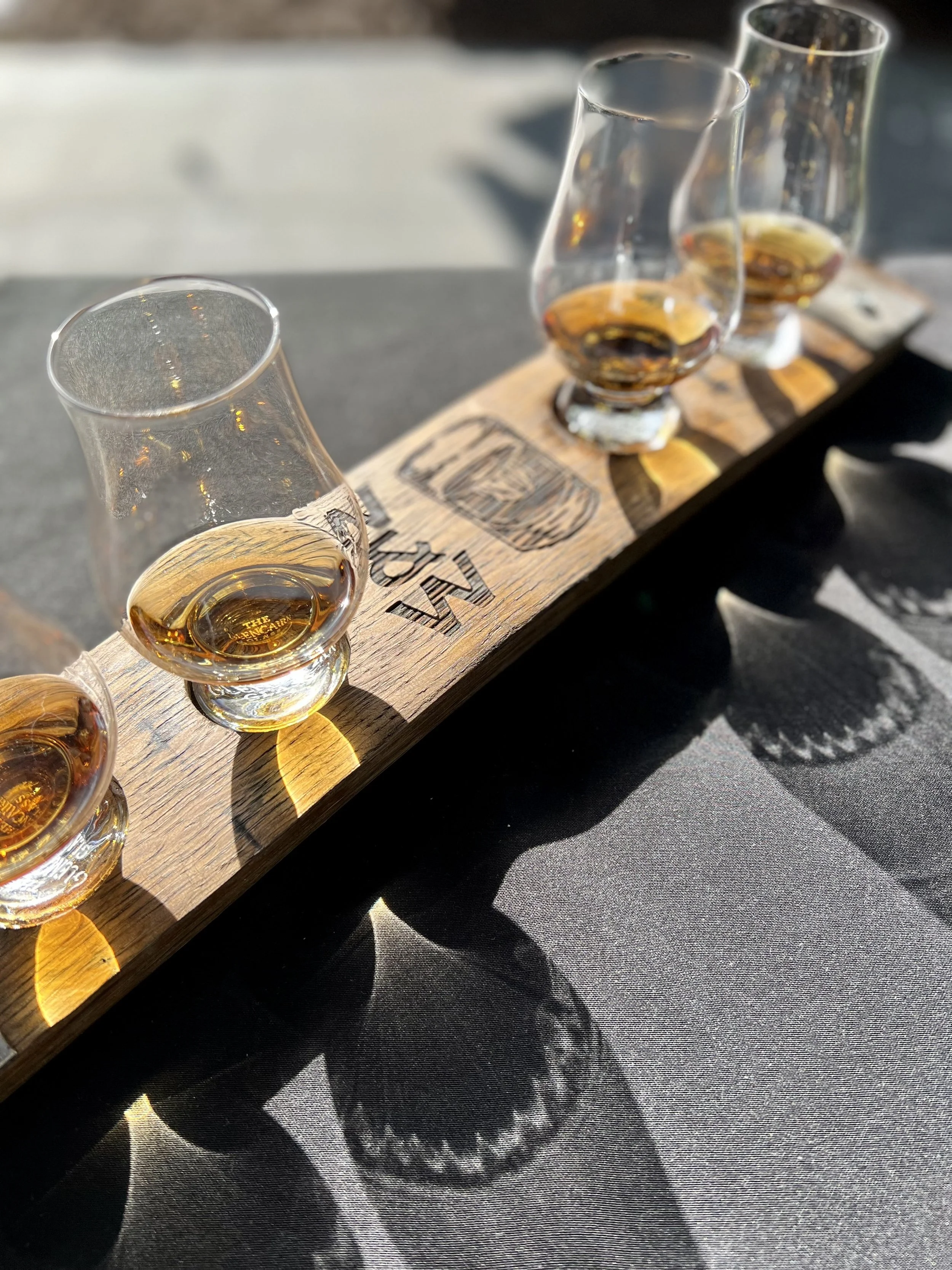 A bourbon flight on a barrel-stave paddle branded Whiskey and Water — one of the largest bourbon collections in North Georgia, at the bourbon bar in Blue Ridge, GA